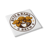 Close-up diagonal view of square white ceramic coaster printed with Byte & Bark Brew® logo