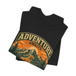 Black folded unisex t-shirt with vintage circular 'Adventure Awaits' mountain and dog graphic