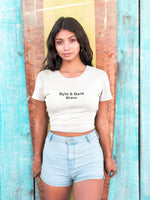 Woman wearing cream cropped T-shirt printed with Byte & Bark Brew® text, high-waisted light denim shorts