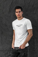 Male model wearing white crewneck T-shirt with centered 'Byte & Bark Brew®' text, dark textured wall background