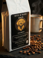 Byte & Bark Brew® Colombia whole-bean coffee bag with dog logo, scattered beans and steaming mug
