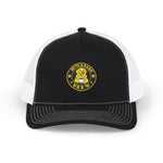 Front view of black and white trucker cap with embroidered Byte & Bark Brew® golden retriever patch