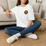 Woman seated cross-legged wearing white oversized tee with Byte & Bark Brew® circular golden retriever logo