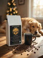 White Byte & Bark Brew® hazelnut coffee bag with scattered beans and steaming black mug, dog blurred behind