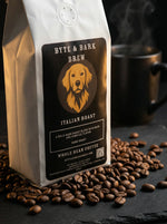 White Byte & Bark Brew® coffee bag with dog logo, spilled whole beans and steaming mug