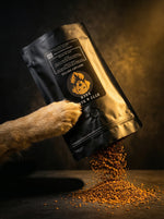 Golden dog paw tipping Byte & Bark Brew® black pouch spilling instant coffee granules onto dark surface
