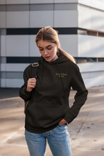 Young woman wearing a dark hoodie with green 'Byte & Bark Brew®' logo on chest and backpack strap visible