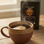 Steaming ceramic mug of black coffee on wood table with Byte & Bark Brew® box behind