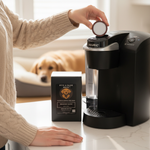 Hand placing single coffee pod into Keurig machine beside Byte & Bark Brew® box